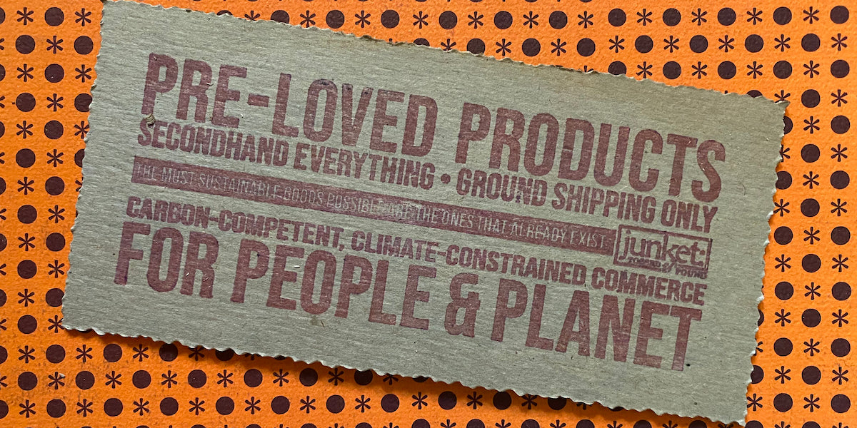Graphic text stamped on cardboard against an orange patterned background. Stamp reads: Pre-Loved Products For People & Planet. Secondhand Everything • Ground Shipping Only • Carbon-Competent, Climate-Constrained Commerce