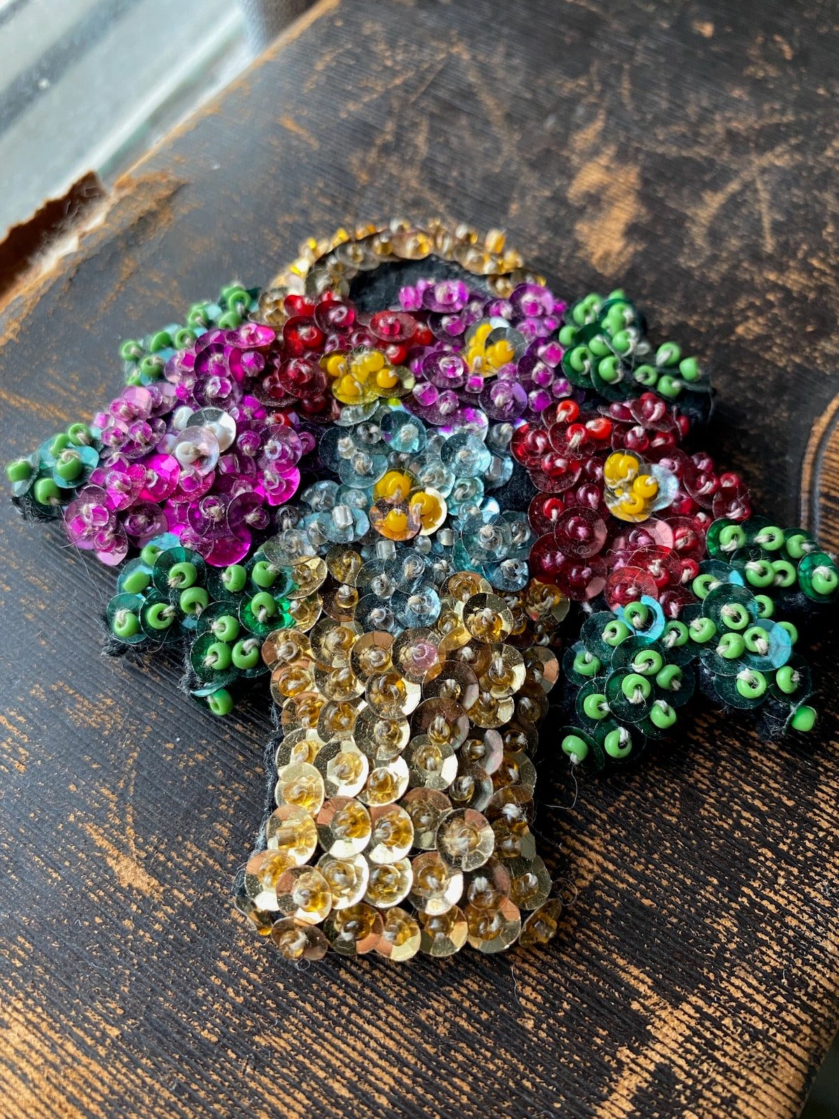 Decorative brooch with multicolored beads on a wooden surface