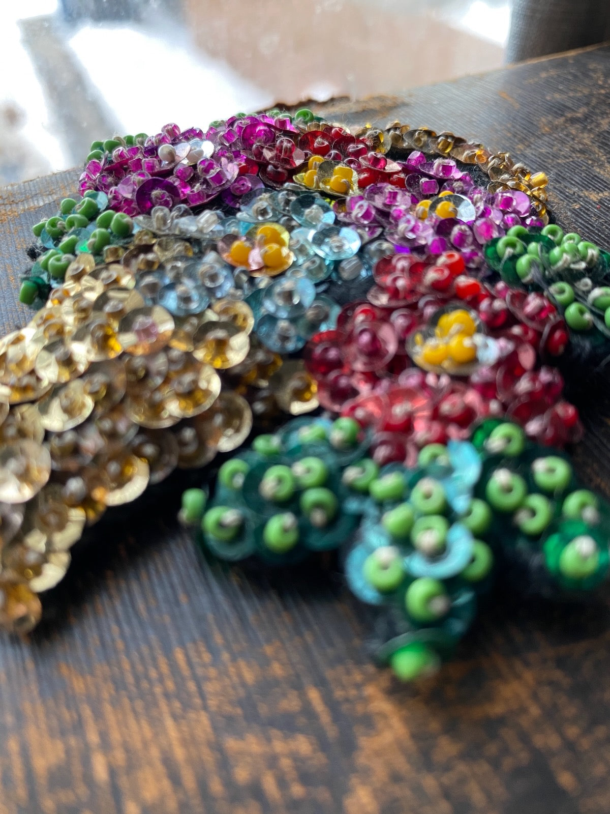 Colorful sequin flowers on a wooden surface