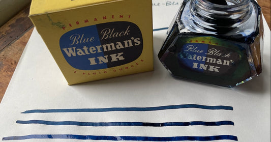 Waterman's Blue Black ink bottle and packaging on a sheet of paper with lines of the representative ink: fresh, settling, and dried (dip pen on Crane paper).