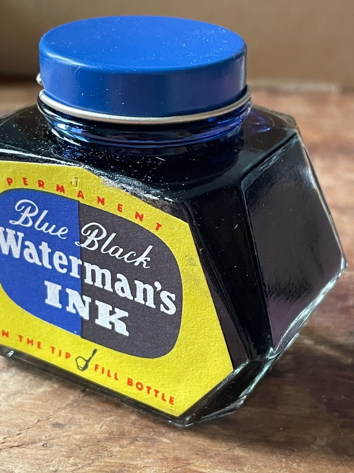Waterman's ink bottle with blue cap on a wooden surface