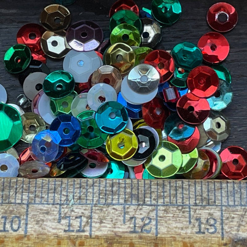 Mixed colorful sequins in different sizes beside a ruler